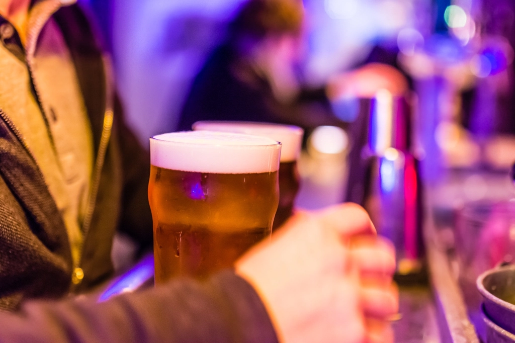 Cold glasses of beer on a bar counter with people in the background
